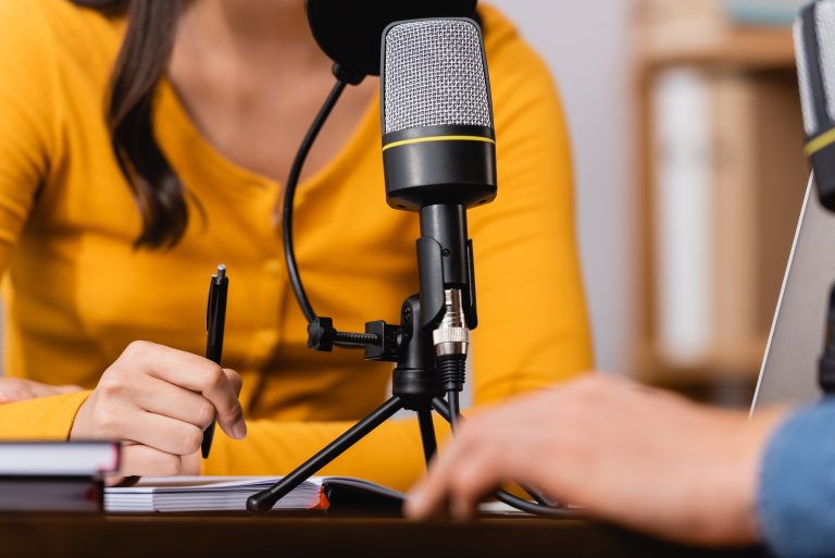 cropped view of broadcaster holding pen during interview with man in radio studio